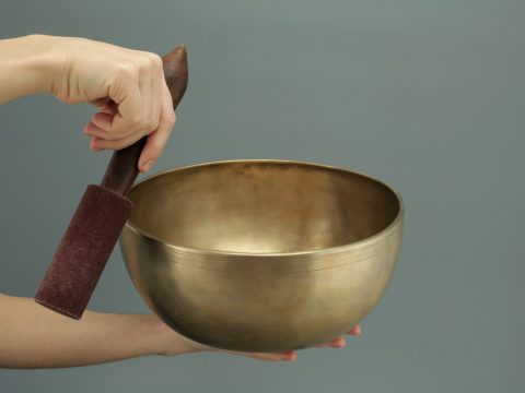 person holding brass-colored song bowl set