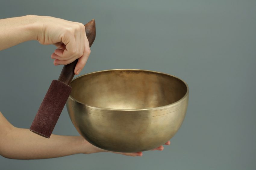 person holding brass-colored song bowl set