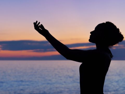 silhouette of woman raising her right hand