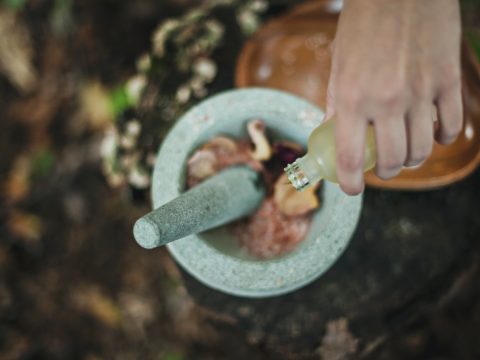 high angle photo of person pouring liquid from bottle inside mortar and pestle