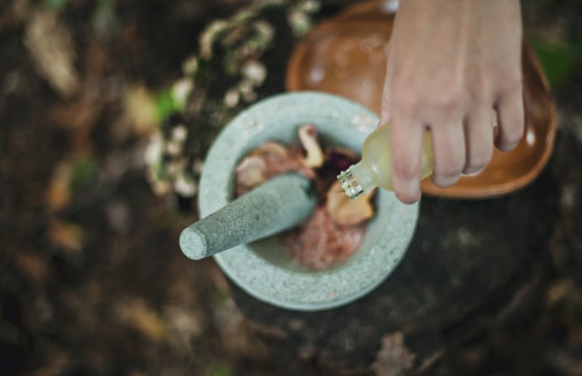 high angle photo of person pouring liquid from bottle inside mortar and pestle