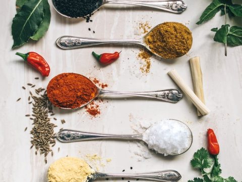 five gray spoons filled with assorted-color powders near chilli